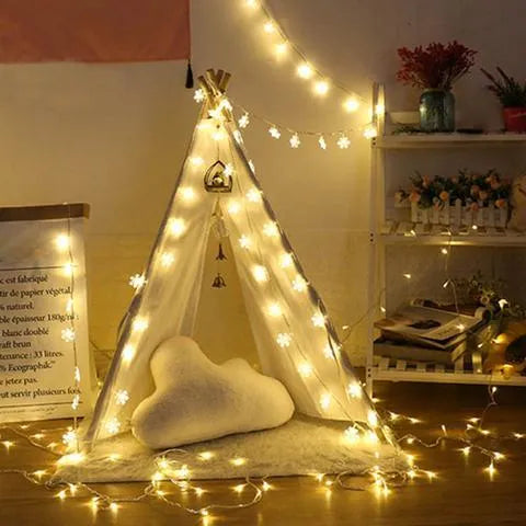 Battery powered LED snowflake string lights with star decorations lit on a dark background