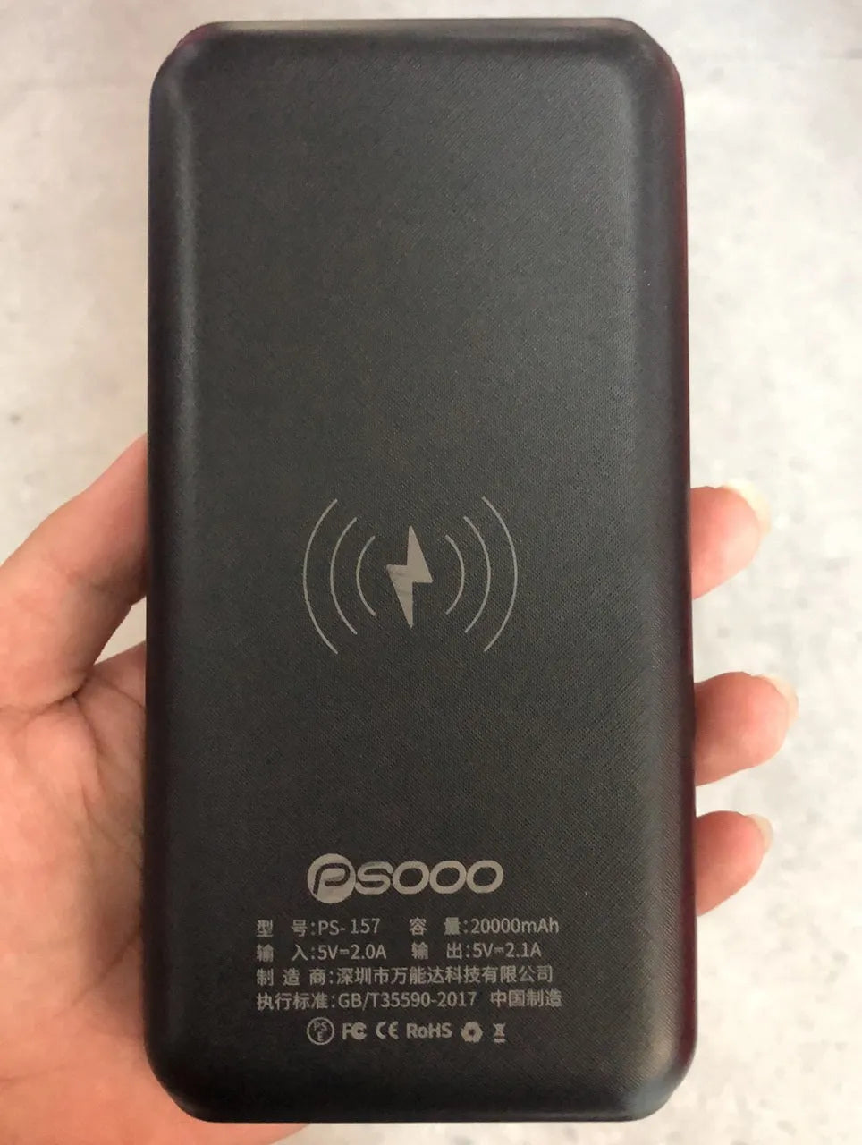 Black wireless power bank with Qi charging pad, three USB ports, and LED flashlight showing capacity display.