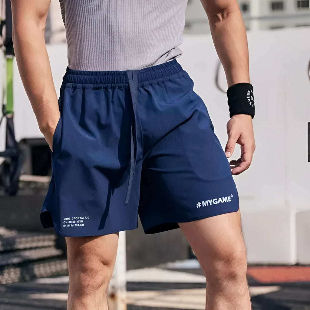 Men's grey fitness training shorts made of quick-dry polyester fabric on a plain background.