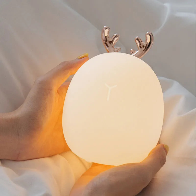 Cartoon deer silicone night light with USB charging cable and touch switch on a bedside table