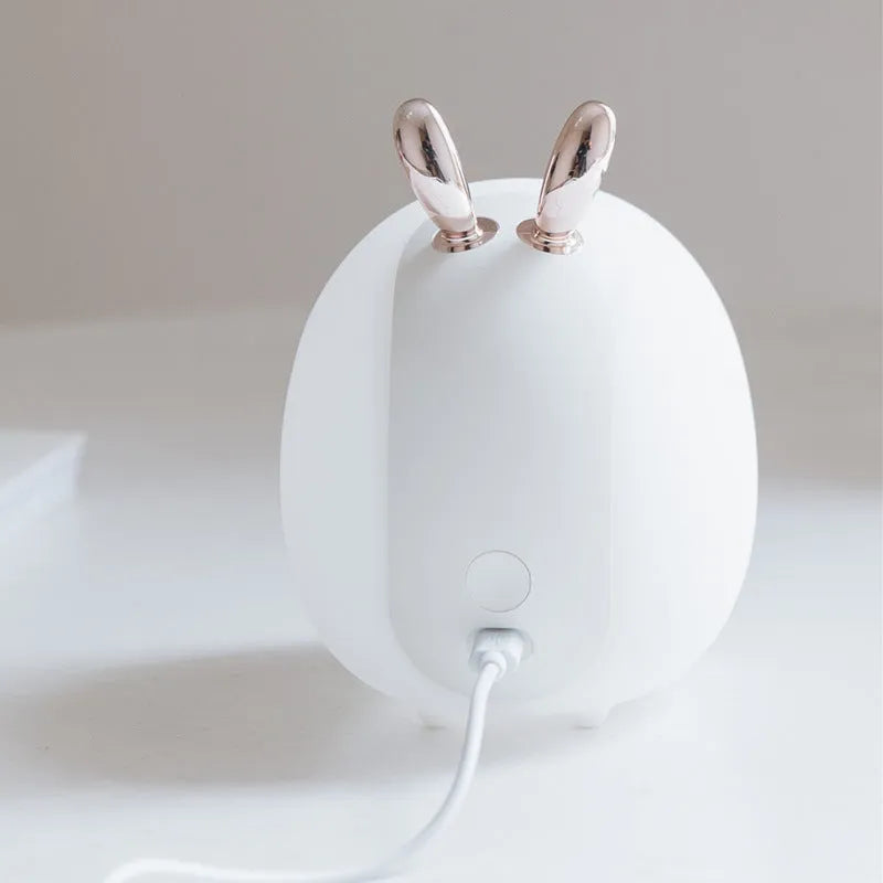 Cartoon deer silicone night light with USB charging cable and touch switch on a bedside table