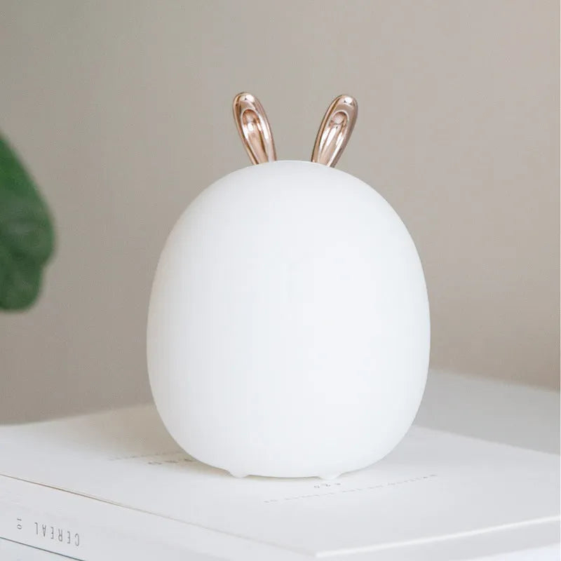 Cartoon deer silicone night light with USB charging cable and touch switch on a bedside table