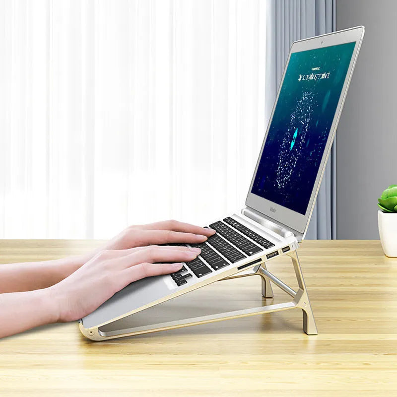 Silver aluminium laptop stand with tablet storage slot underneath, holding a MacBook and an iPad on a desk