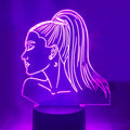 Black based LED desk lamp with colourful acrylic shade and a small remote control on a wooden desk.