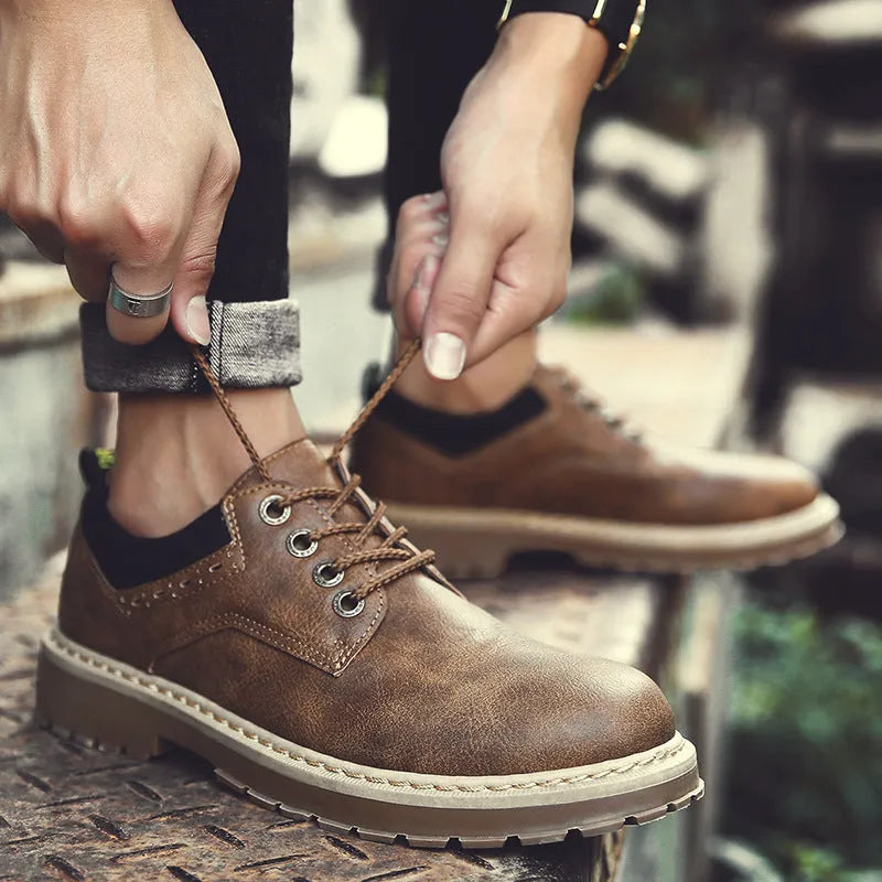 Men's black casual shoes with round toe, flat heel, and front lace-up design on a plain background.