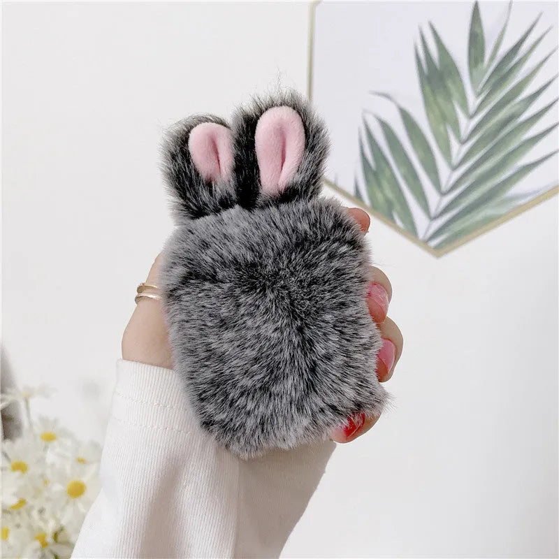 Soft pink silicone AirPod case with rabbit ears design on a grey background.