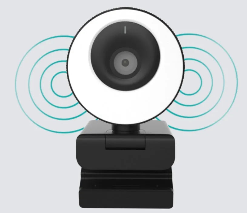 Black USB webcam with magnetic privacy cover on desktop next to computer monitor