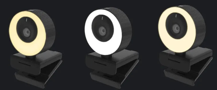 Black USB webcam with magnetic privacy cover on desktop next to computer monitor