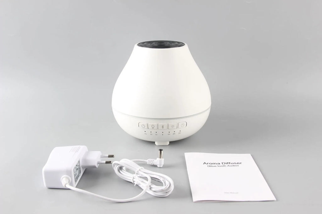 White round Bluetooth humidifier and essential oil aroma diffuser with night light on a table.