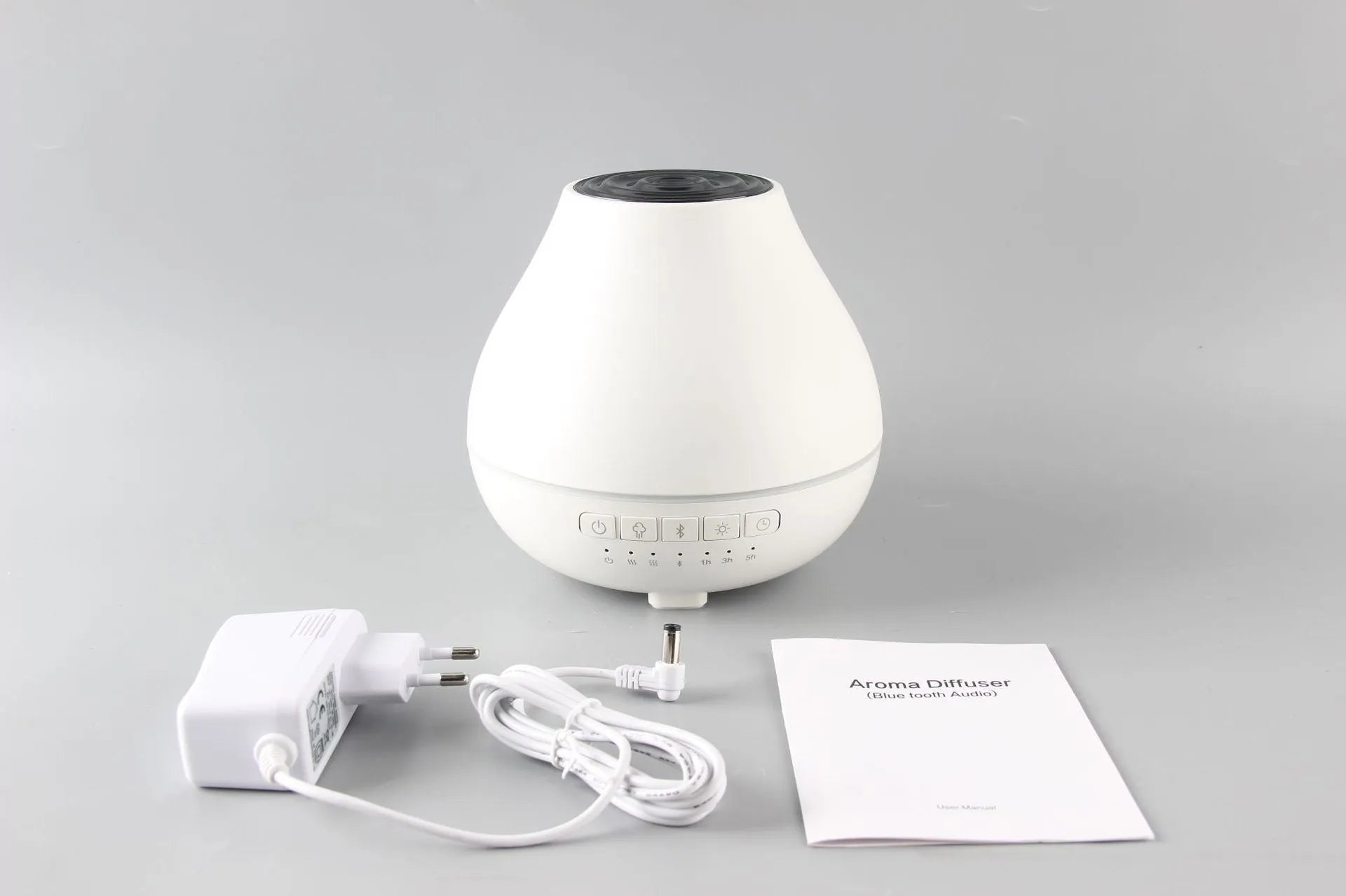 White round Bluetooth humidifier and essential oil aroma diffuser with night light on a table.