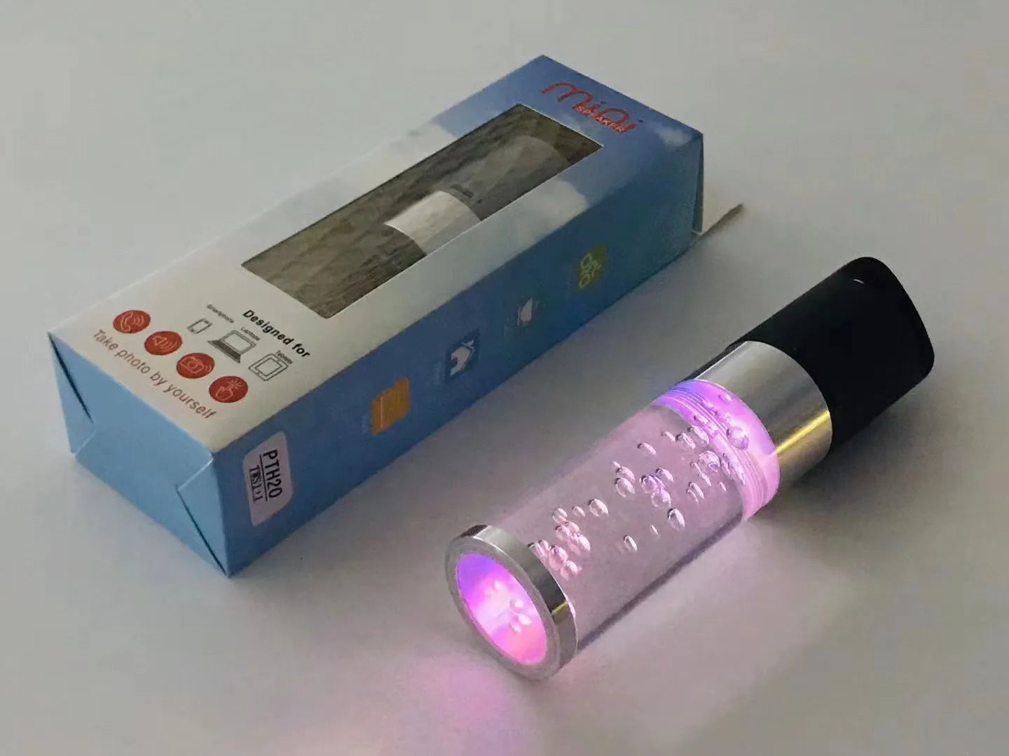 Pink cartoon-style portable Bluetooth speaker with colourful crystal lights on a desk.