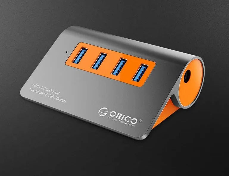 Dark grey aluminium USB-C hub with orange accents showing four USB 3.1 ports and separate data cable