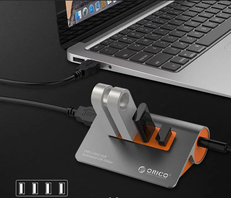 Dark grey aluminium USB-C hub with orange accents showing four USB 3.1 ports and separate data cable