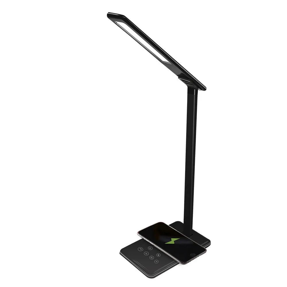 Black wireless charging LED desk lamp with touch control and USB cable on a wooden desk.