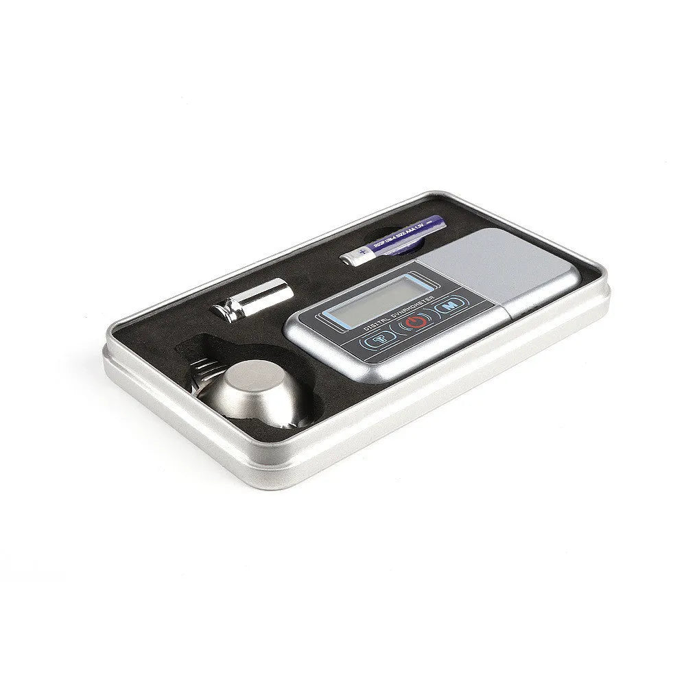 A compact digital electronic scale with a 100g capacity and 0.005g precision, shown weighing small items.