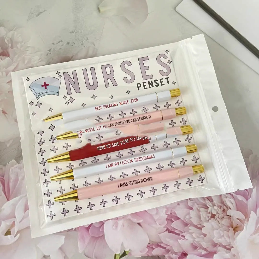 Set of five white plastic retractable ballpoint pens with blue and red nurse-themed humorous text printed on the barrels.