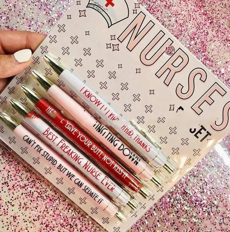 Set of five white plastic retractable ballpoint pens with blue and red nurse-themed humorous text printed on the barrels.