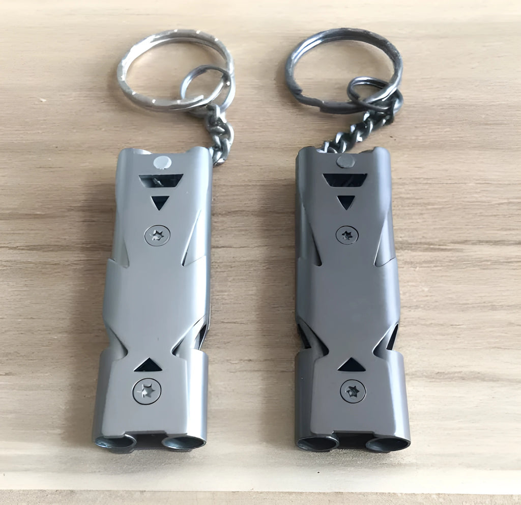 Keychain whistle in black with metal lanyard ring on a plain background