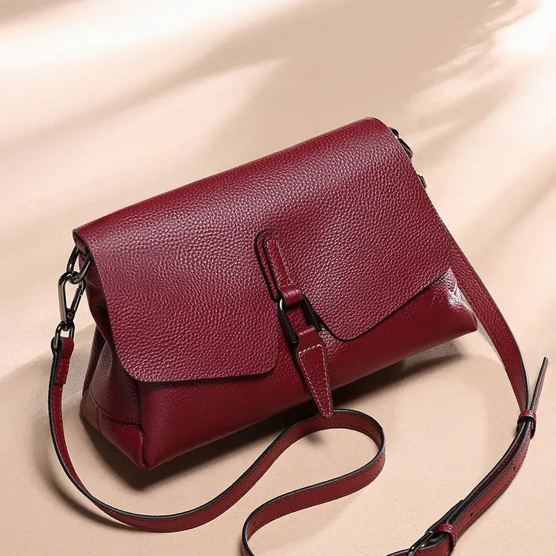 Women's soft cowhide shoulder bag in Wine Red with three main pockets and adjustable strap on white background
