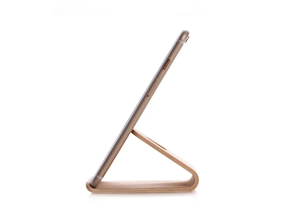 Wooden iPhone stand in walnut finish on a desk holding a mobile phone.
