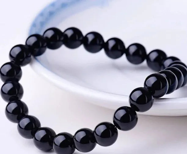 Black onyx geometric bead bracelet with elastic cord on a wrist.