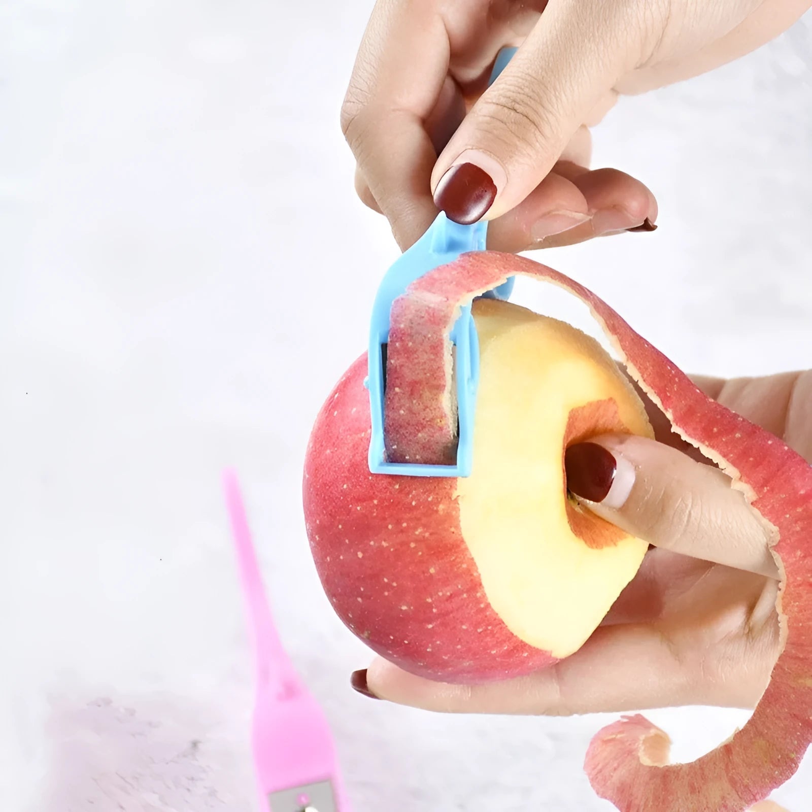 Multifunctional fruit peeler with finger ring and stainless steel blade in pink, blue, and orange colours