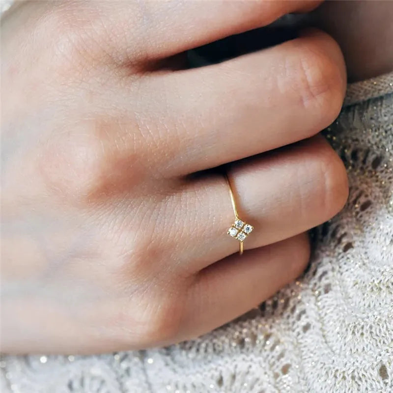 Four heart-shaped motif gold rings with zircon stones set on a dark surface
