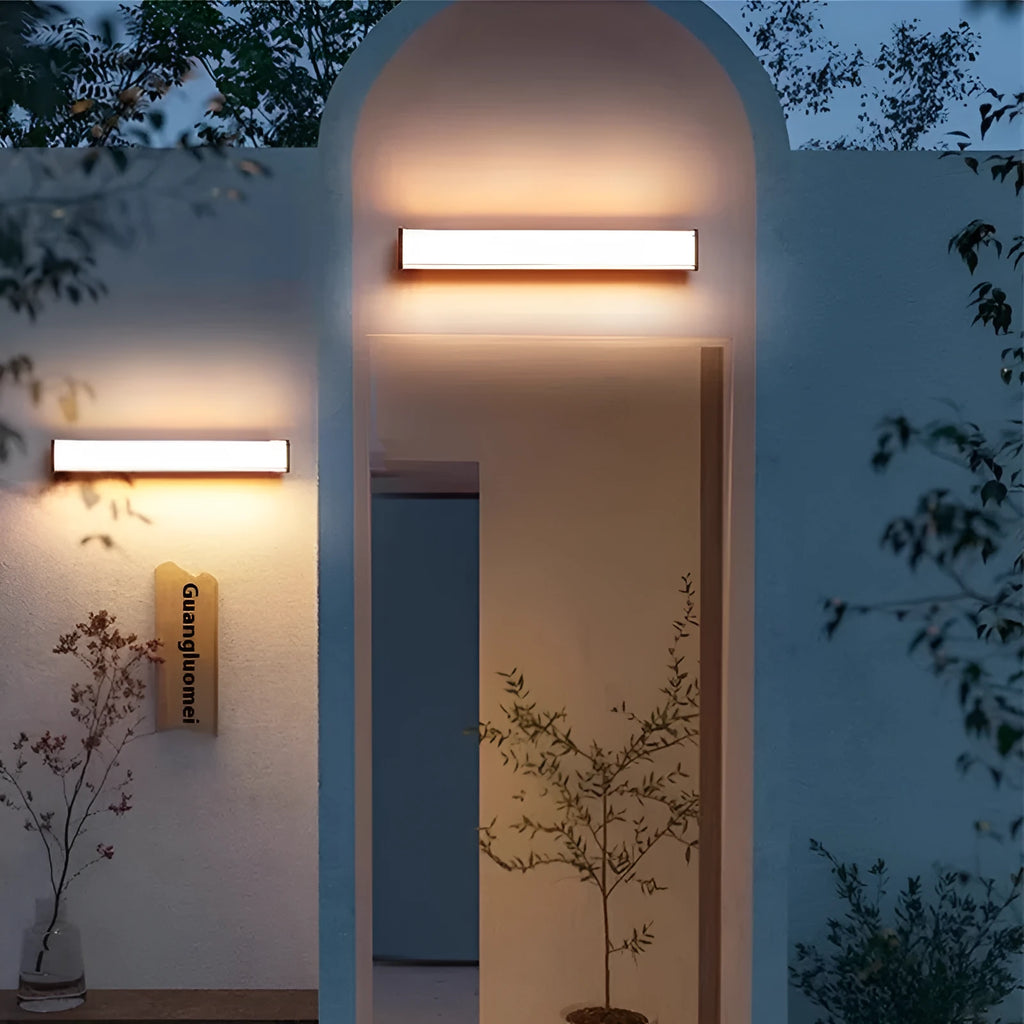 Modern outdoor wall lamp mounted on stone wall, showing clean lines and illuminated light source.