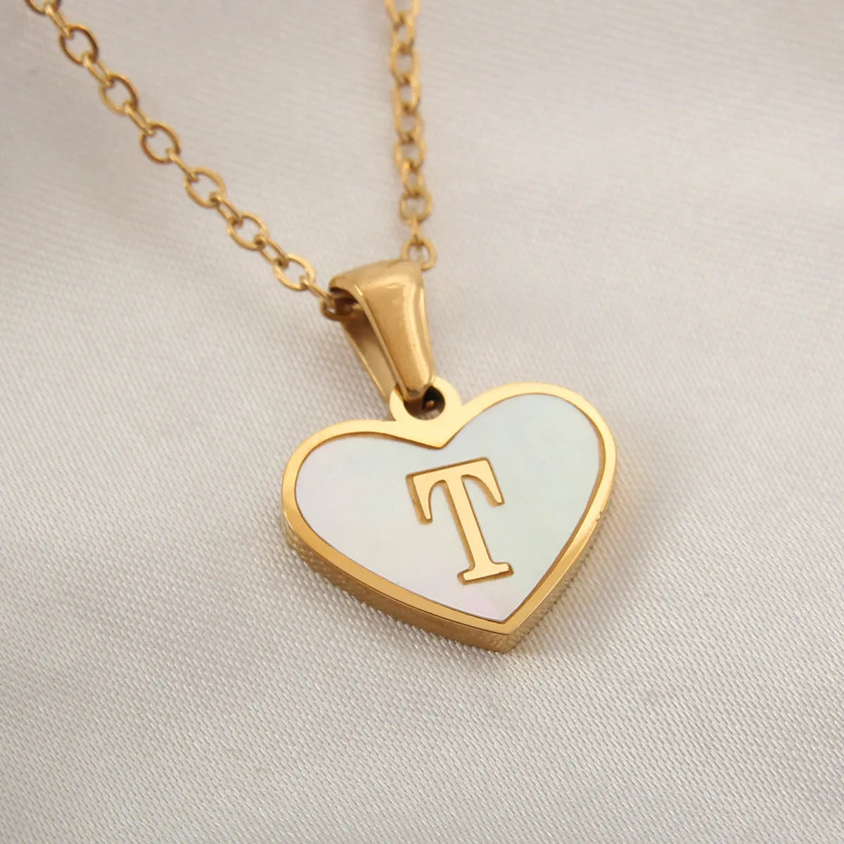 Gold plated heart-shaped necklace with a personalised initial letter and white shell detail on a 50cm adjustable chain.
