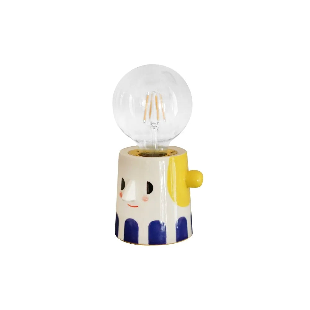 Handmade ceramic bedside lamp with ball headlight colour design on a table.