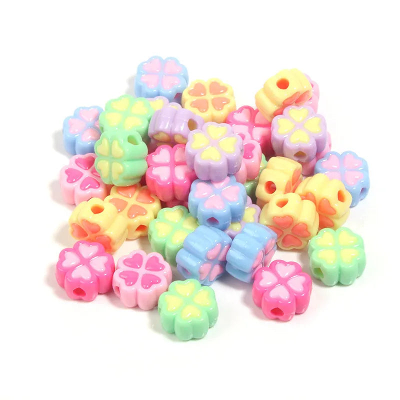 A selection of 15mm frosted acrylic beads showing a raised cartoon love and four-leaf clover pattern in various colours.