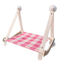 Pink wooden cat hammock with suction cups attached to a window, showing a removable cat paw print fabric seat.