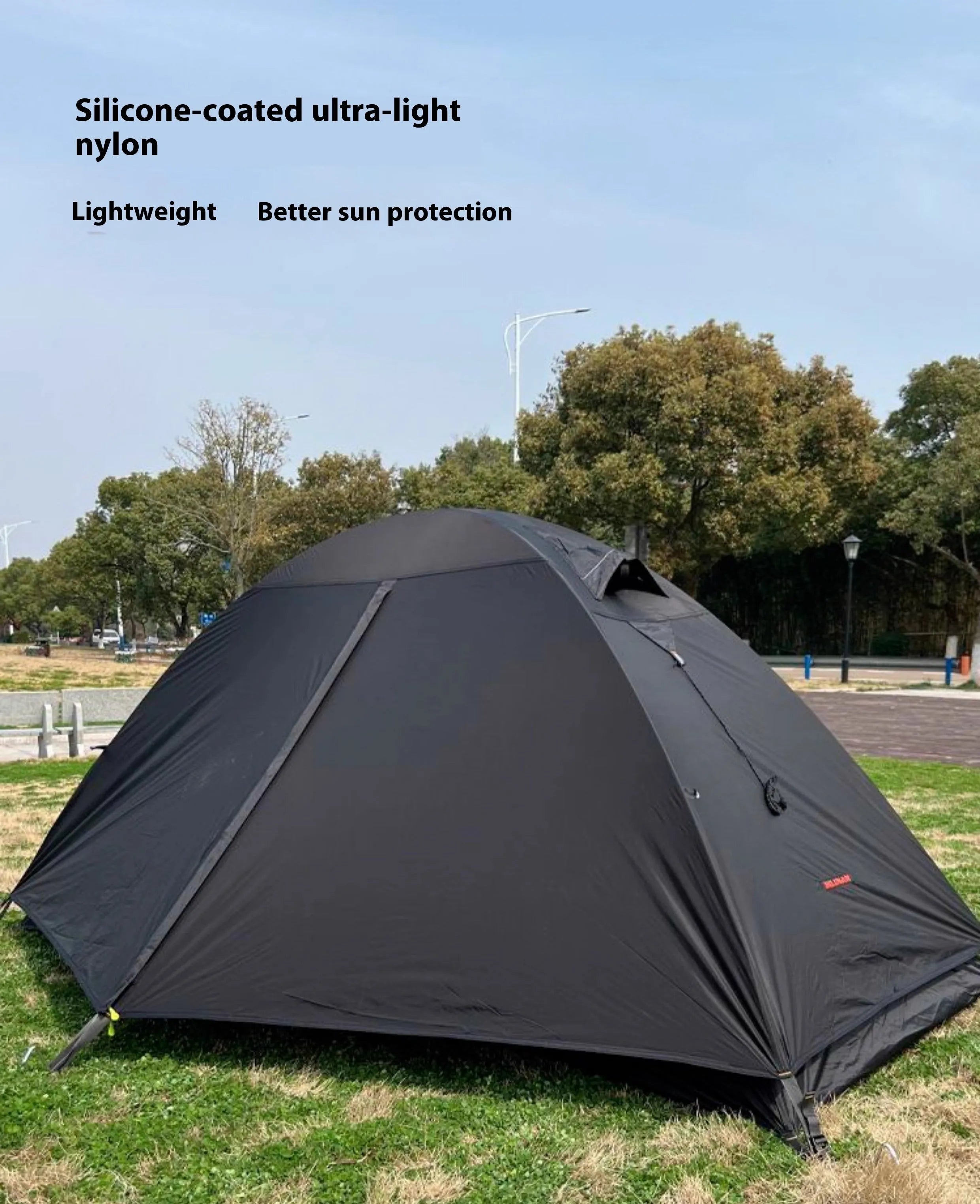 Black single person hiking tent with aluminium poles pitched outdoors, showing double-layer design.