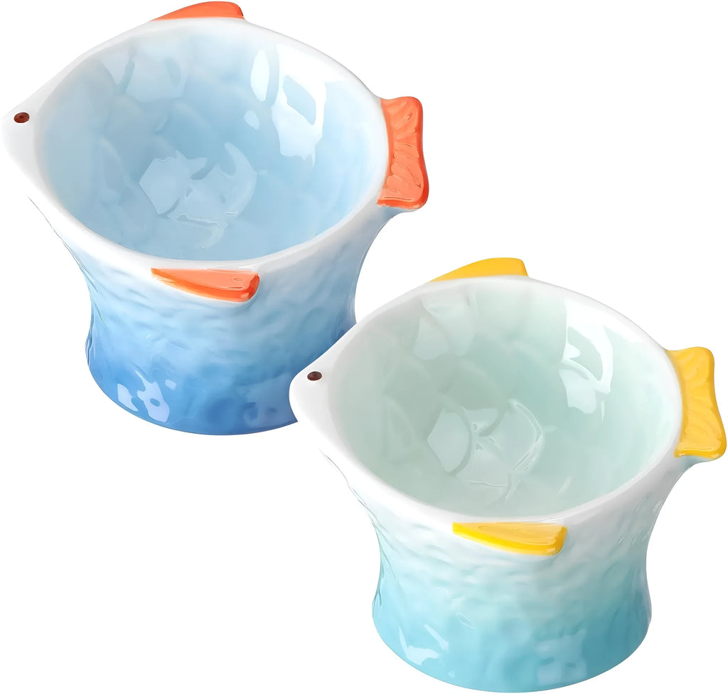 Set of four blue fish-shaped ceramic cat bowls with a tilted angle on a flat surface.