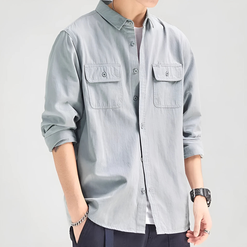 Man wearing a loose grey long sleeve shirt with a cardigan and overalls-inspired design