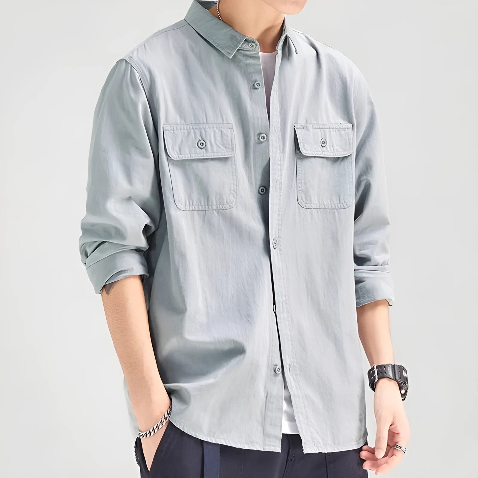 Man wearing a loose grey long sleeve shirt with a cardigan and overalls-inspired design