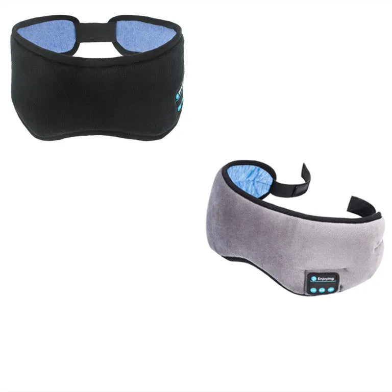 Black Bluetooth sleep mask with built-in speakers lying flat on a surface with a charging cable.