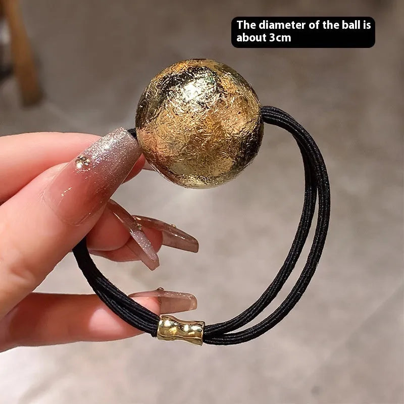 Resin hair band with electroplated gold finish, round head rope style, on a plain background