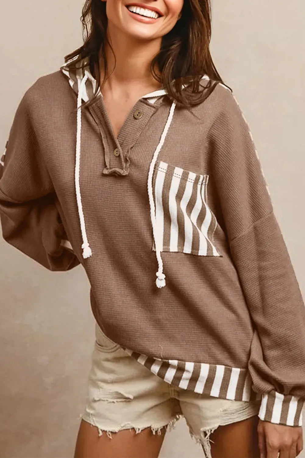 Straw yellow hoodie with striped patchwork design, waffle texture, button neck, and drawstring hood.