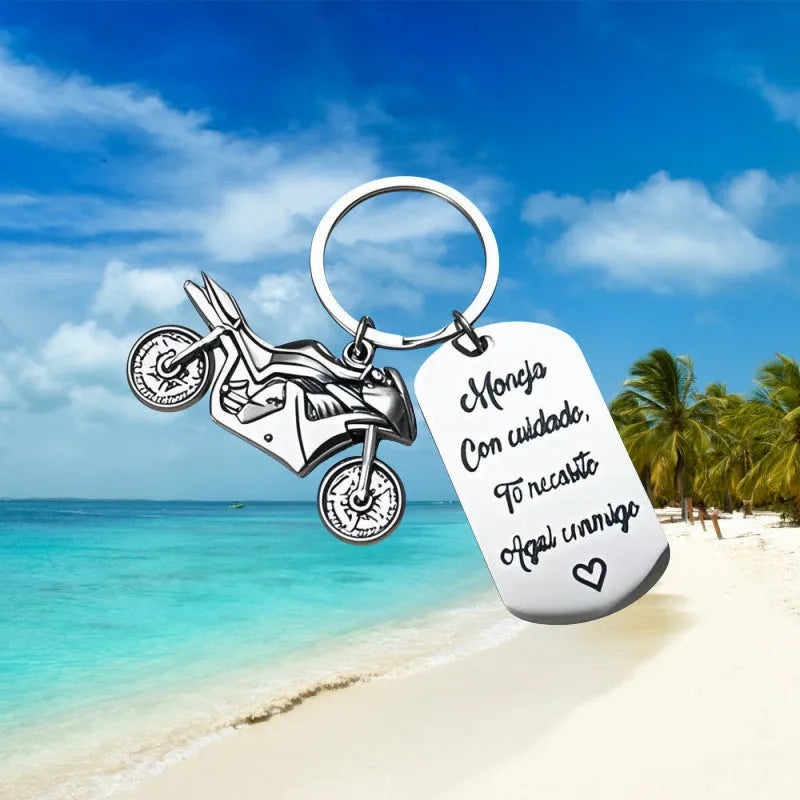 Silver motorcycle charm on a stainless steel key ring next to a red flannel storage bag.