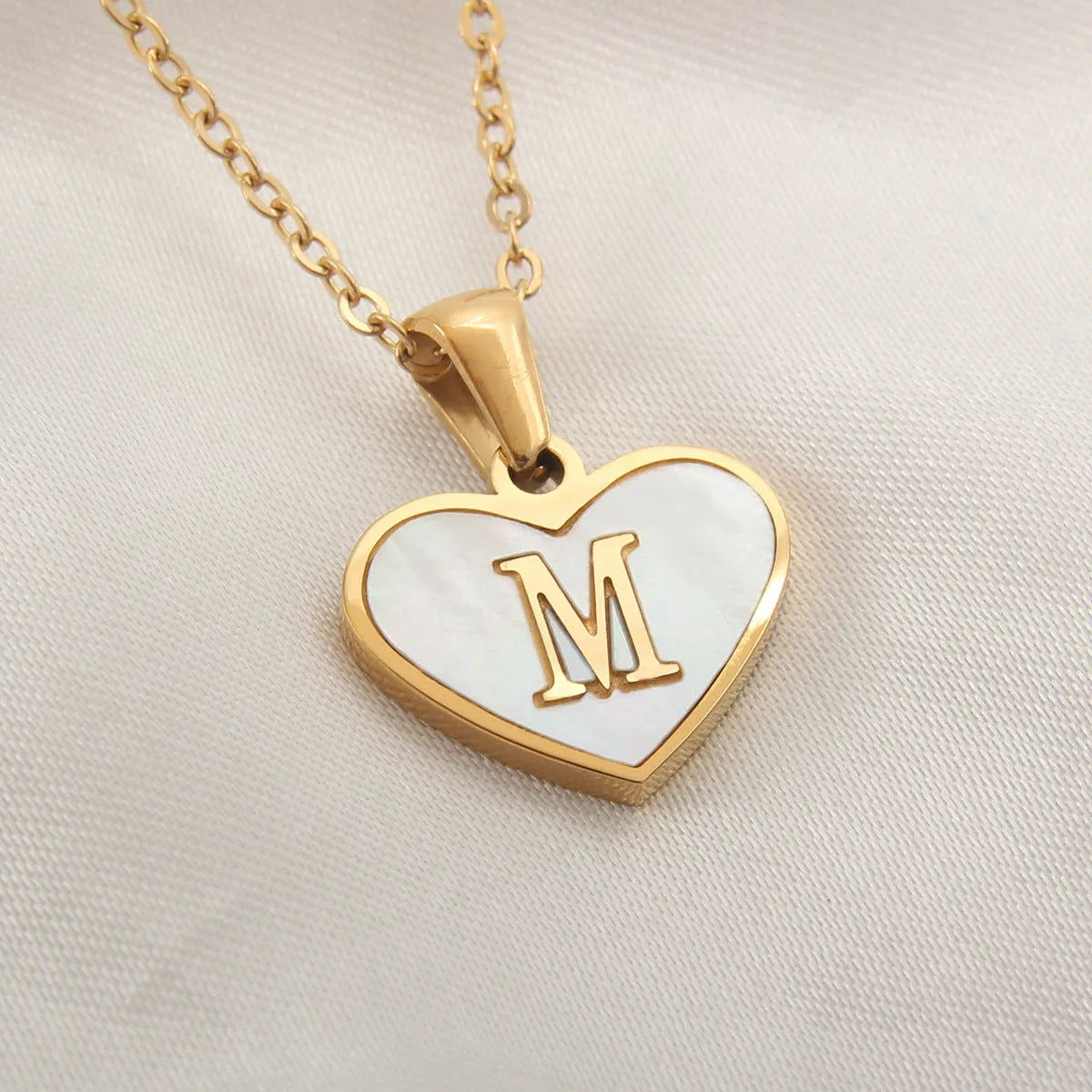 Gold plated heart-shaped necklace with a personalised initial letter and white shell detail on a 50cm adjustable chain.