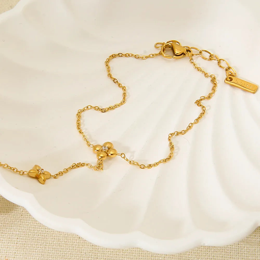 Gold stainless steel bracelet with eight pointed star and flower charms