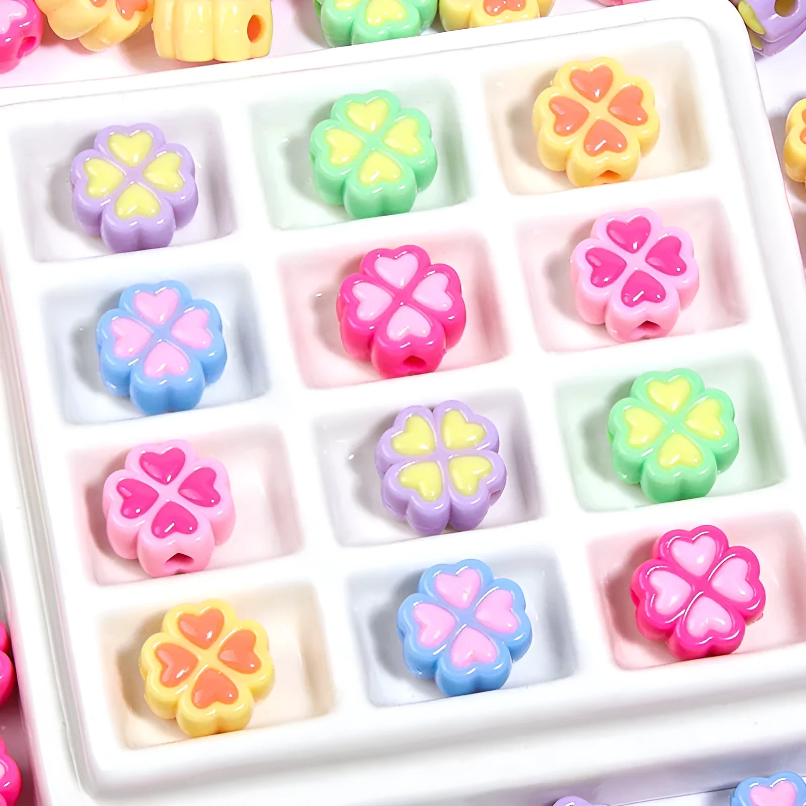 A selection of 15mm frosted acrylic beads showing a raised cartoon love and four-leaf clover pattern in various colours.