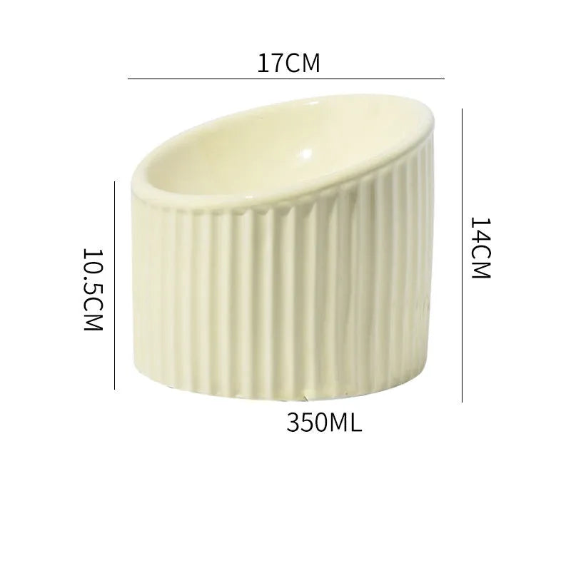 Ceramic elevated cat bowl in light green, showing its tilted, round shape and raised design on a table.