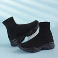 Thick-soled slip-on casual shoes in black with fabric upper, mid-top design, and round toe.