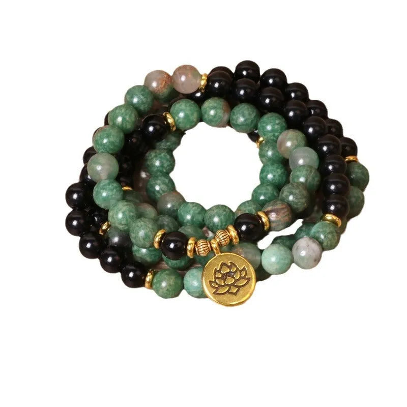 Green and black elastic beaded alloy bracelet on a wrist.