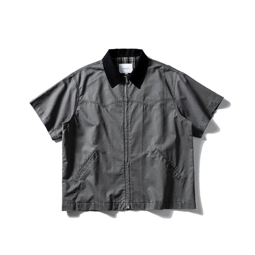 A man's khaki loose-fit short-sleeve cotton overalls shirt with button front and patch pockets.