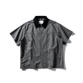A man's khaki loose-fit short-sleeve cotton overalls shirt with button front and patch pockets.