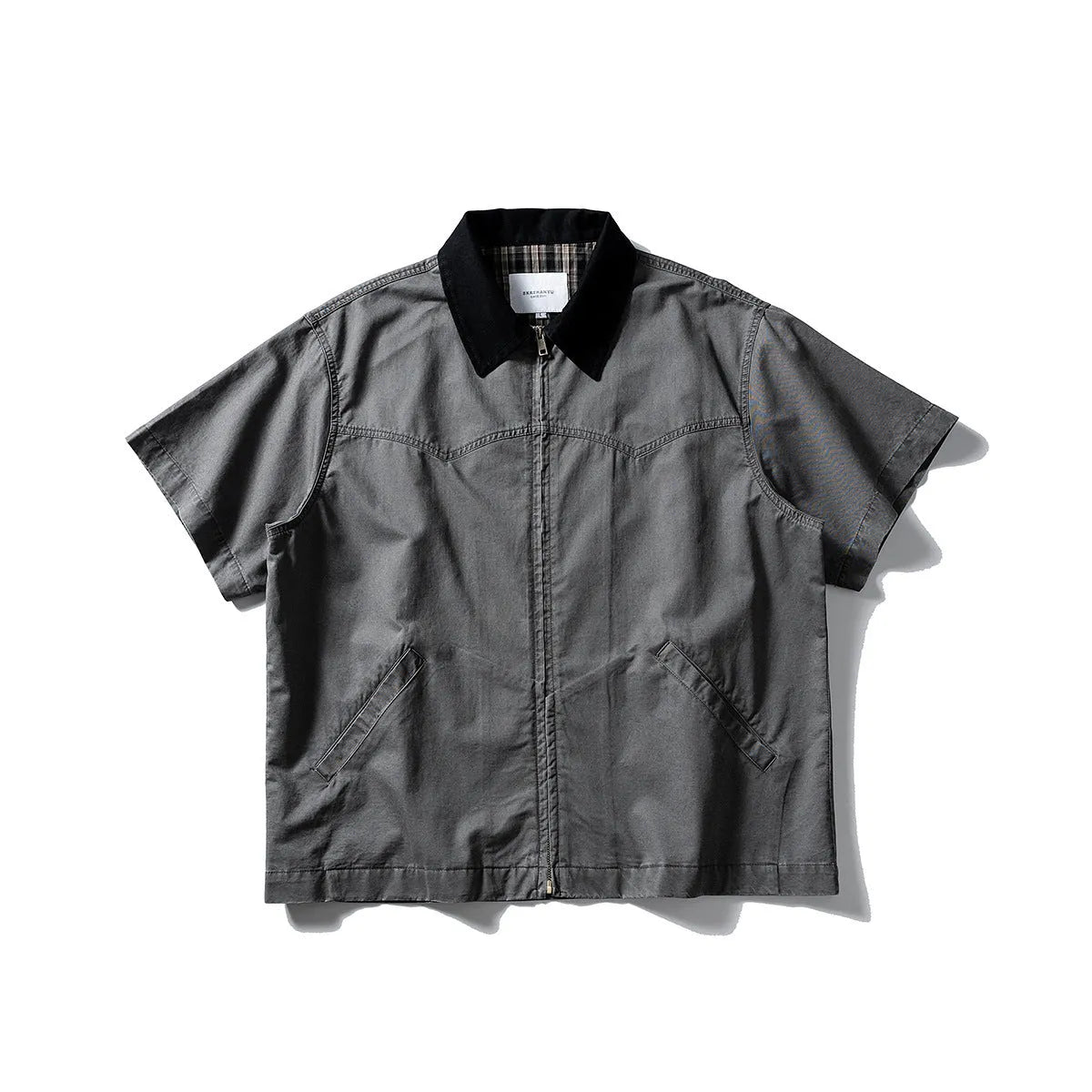 A man's khaki loose-fit short-sleeve cotton overalls shirt with button front and patch pockets.