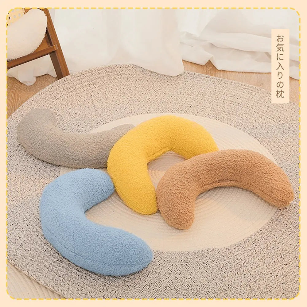 Blue U-shaped cat pillow with an adjustable fabric collar on a grey sofa